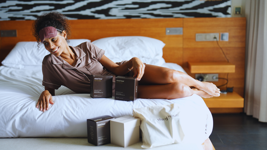 Person stretching in bed near a bright window