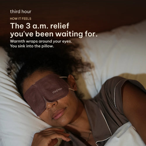 The 3 a.m. relief you've been waiting for. A woman curled up in bed wearing a Third Hour warming sleep mask.