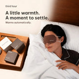 A little warmth. A moment to settle. Third Hour sleep mask warms automatically, worn in bed beside the bedside table.